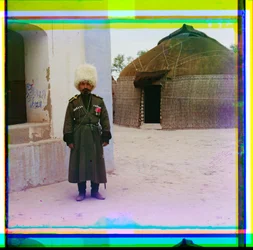 An Armed Man in Uniform Stands Next to Building with a Yurt in the Background, Russia, 1915